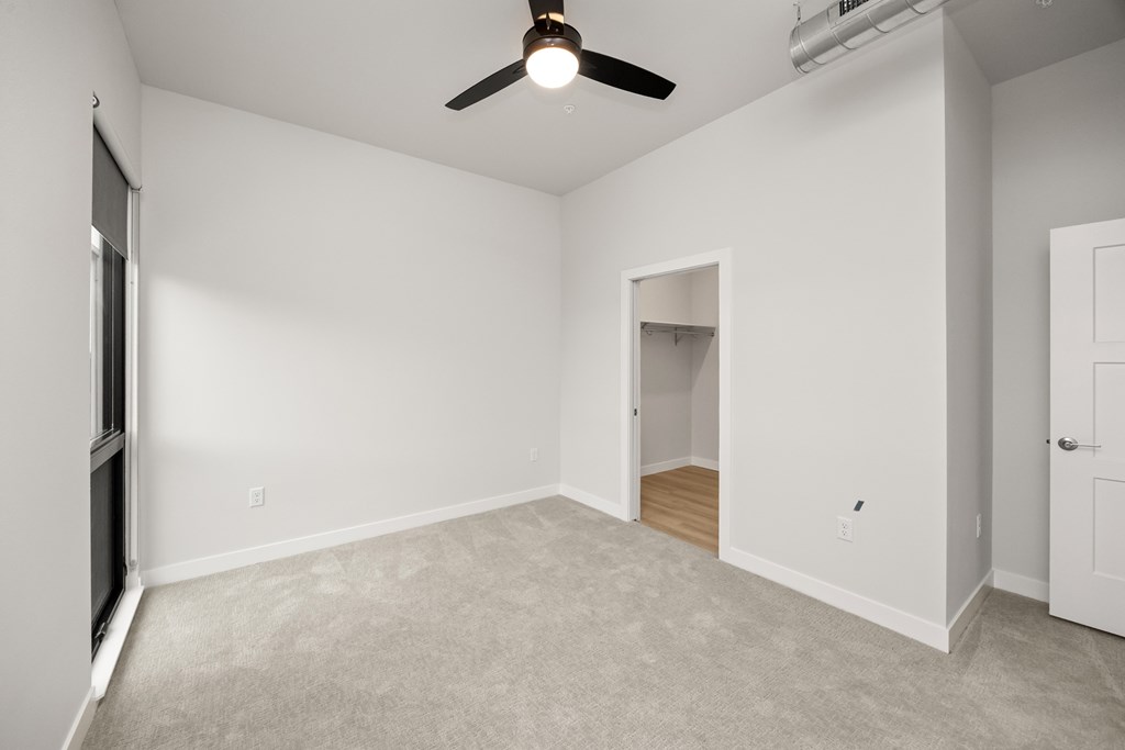 A room with a ceiling fan and a doorway leading to another room.
