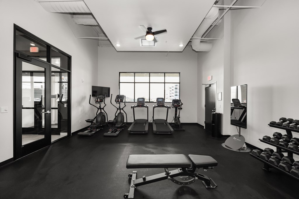 A black and white photo of a gym with a variety of equipment.