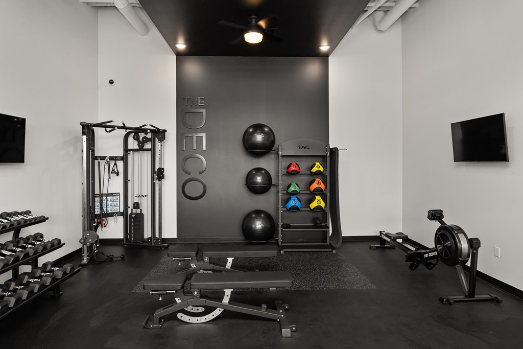 A black and white photo of a gym with a variety of equipment.