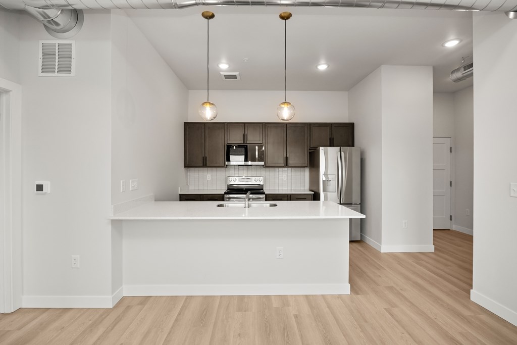 A modern kitchen with a white island and wooden floors.