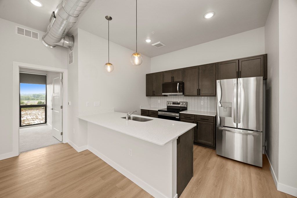 A modern kitchen with a white countertop and stainless steel appliances.