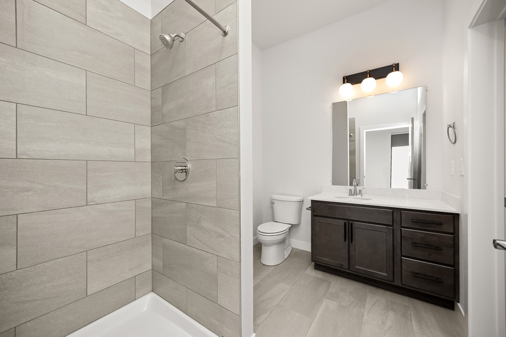 A bathroom with a toilet, sink, and a shower.