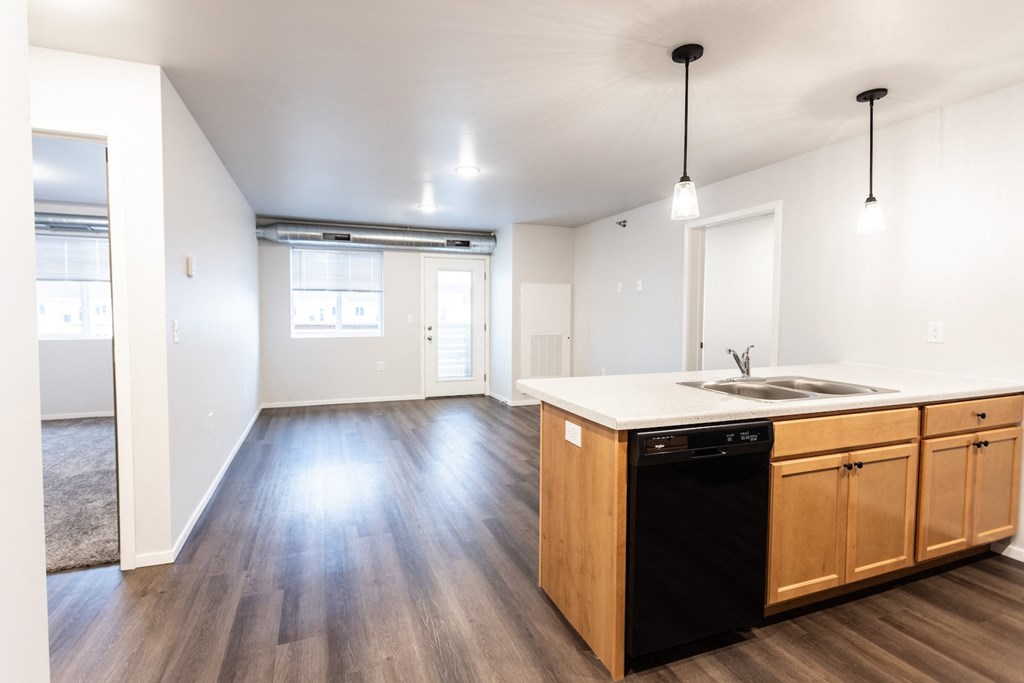 an empty kitchen and living room with wood flooring and white walls