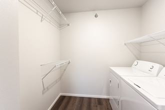 a laundry room with a washer and dryer and a white wall with shelves