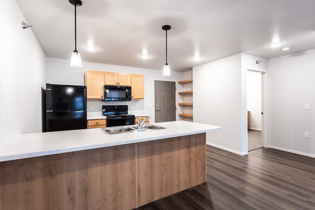 a kitchen with a white counter top and a black refrigerator