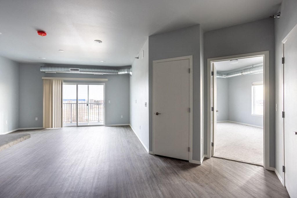 an empty living room with a door to a balcony