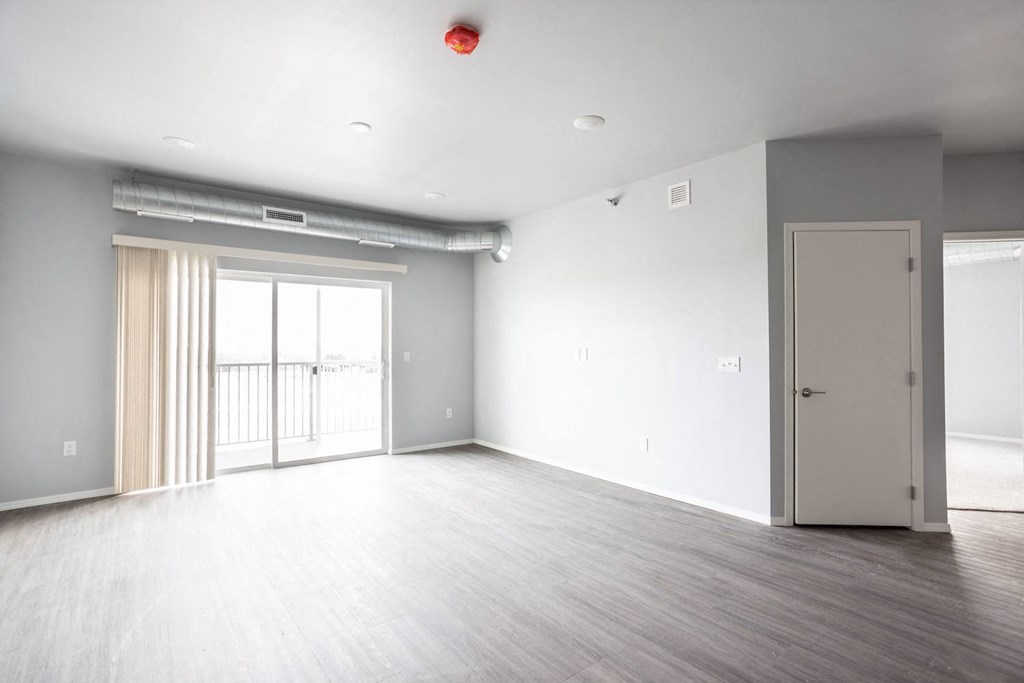 an empty living room with a door to a balcony