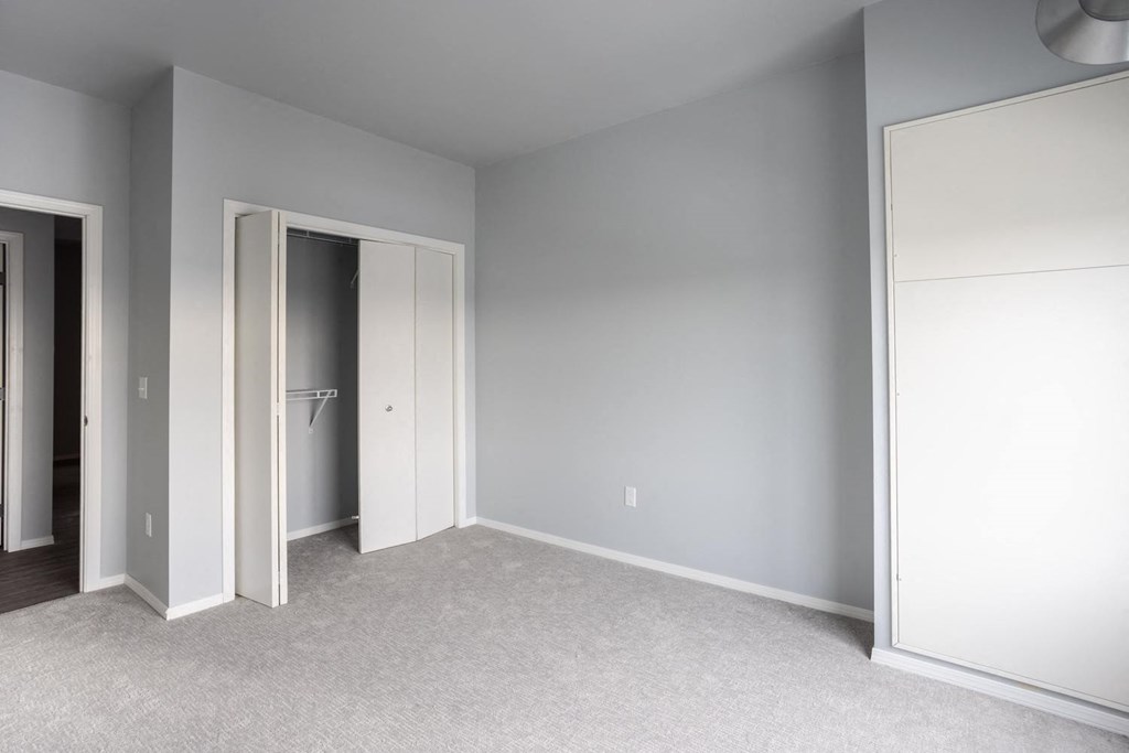 a bedroom with a door to a closet and a carpeted floor