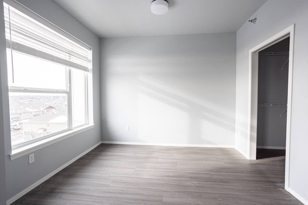 a room with white walls and a large window and wooden floors