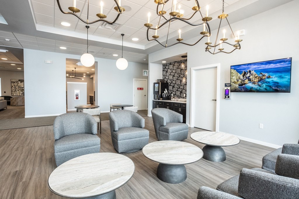 a lobby with chairs and tables and a tv on the wall
