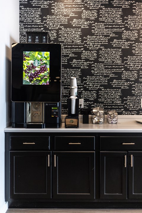 a black kitchen with black cabinets and a tv on a black wall