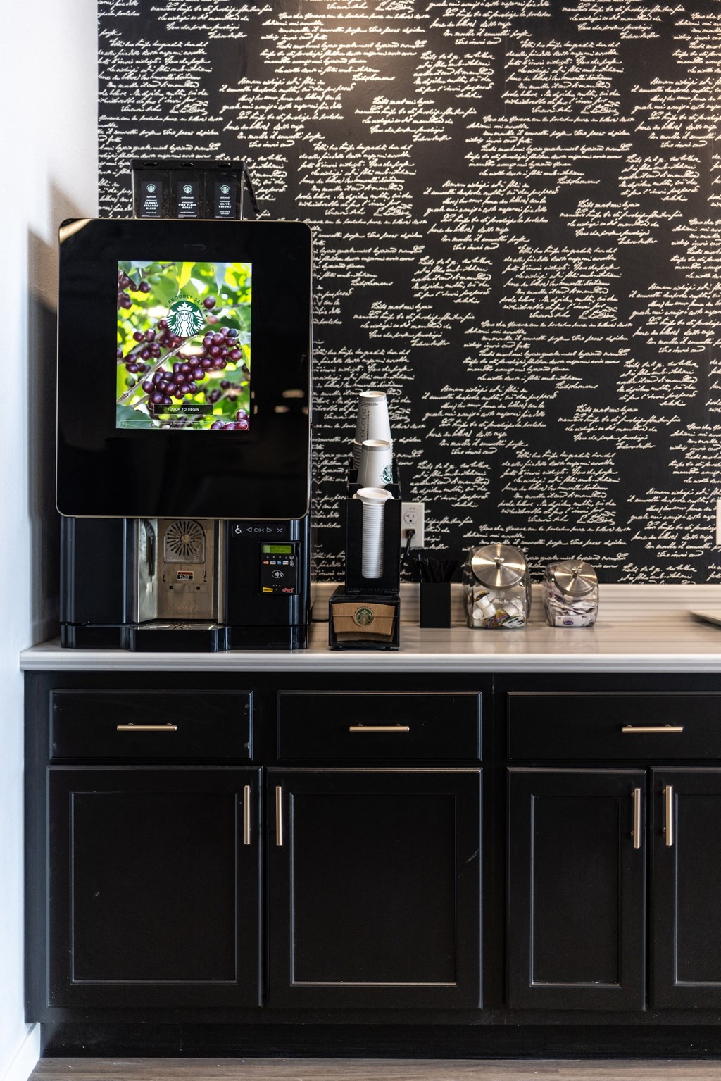 a black kitchen with black cabinets and a tv on a black wall