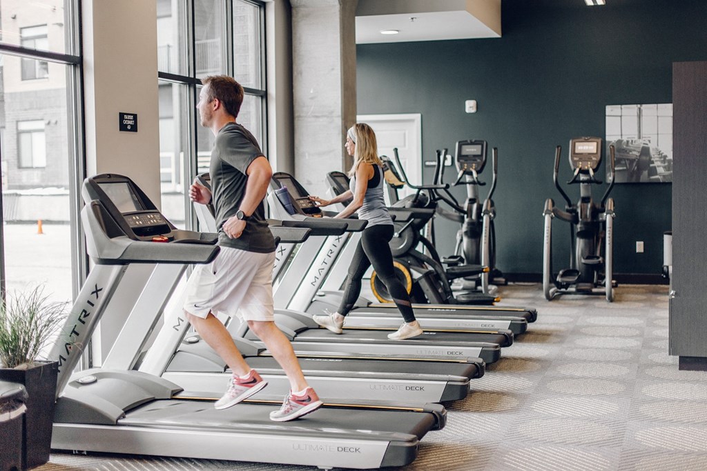 two people running on treadmills in a gym