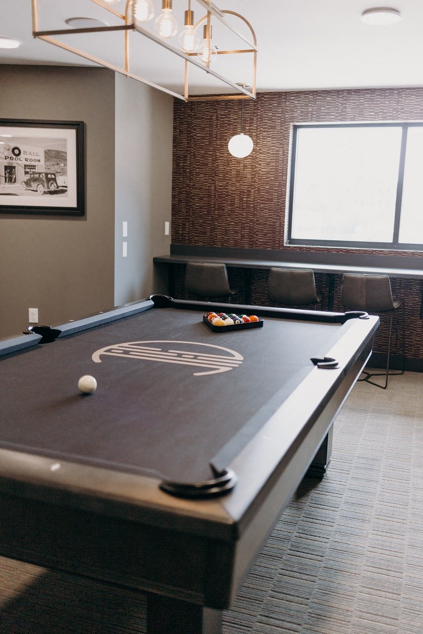 a pool table in a room with two windows and a scoreboard