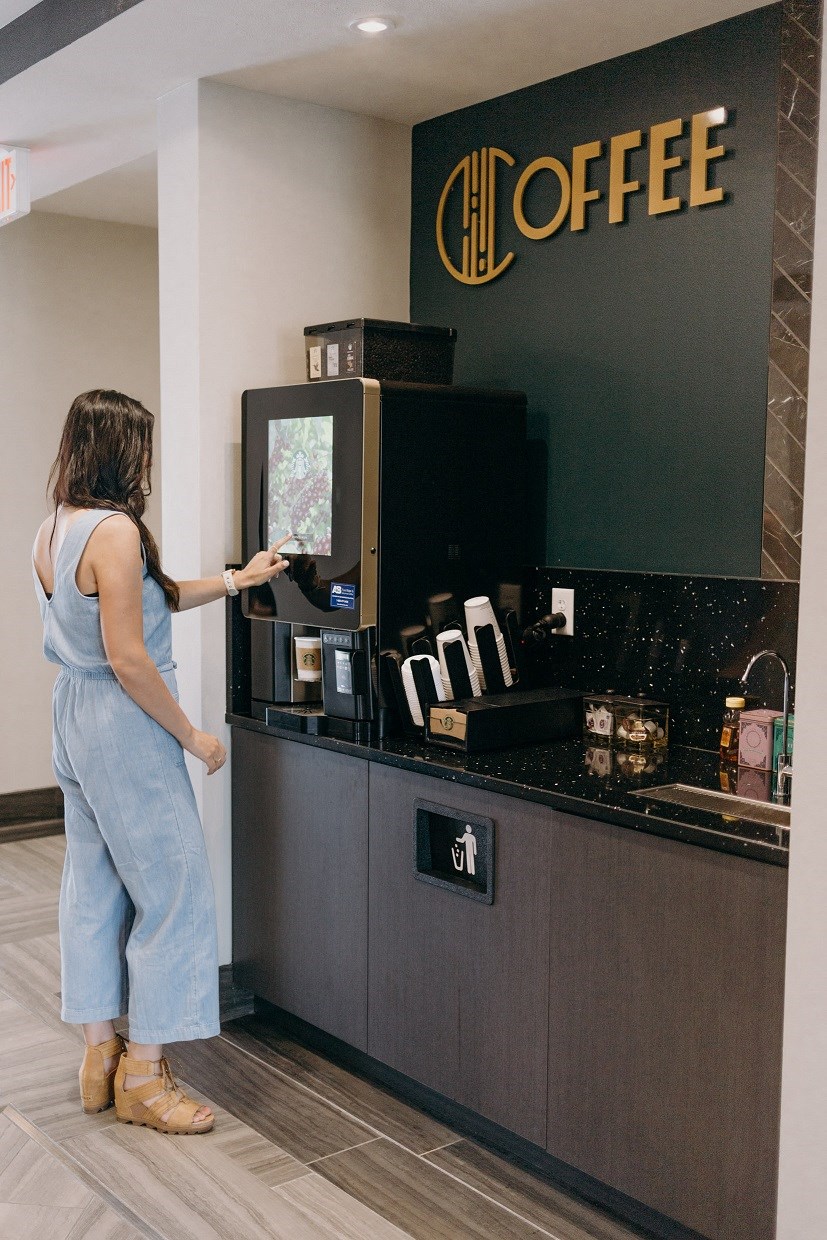 a woman making a purchase at a coffee kiosk at a chic coffee shop