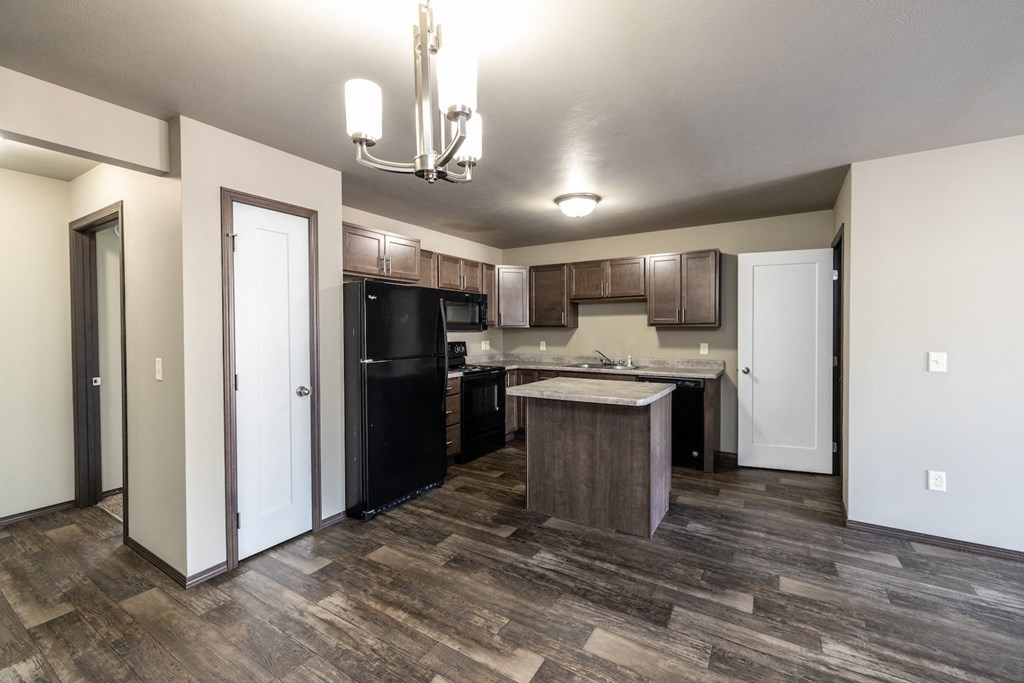 a kitchen with black appliances and wood flooring in a new home