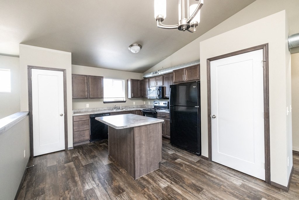 an empty kitchen with a black refrigerator and a sink