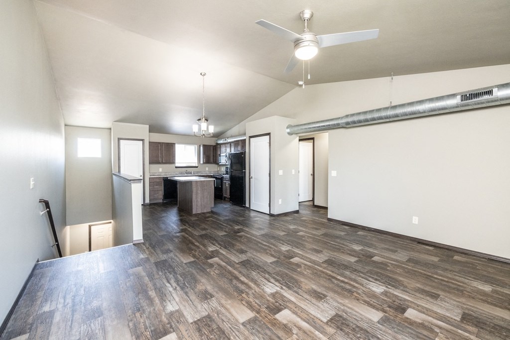 an empty living room and kitchen with a ceiling fan