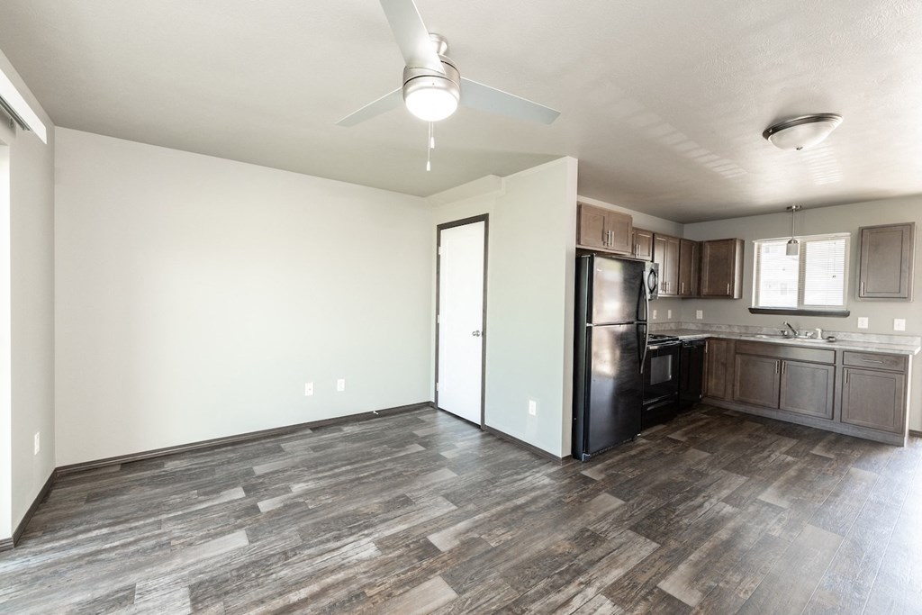 an empty living room and kitchen with a refrigerator and a sink