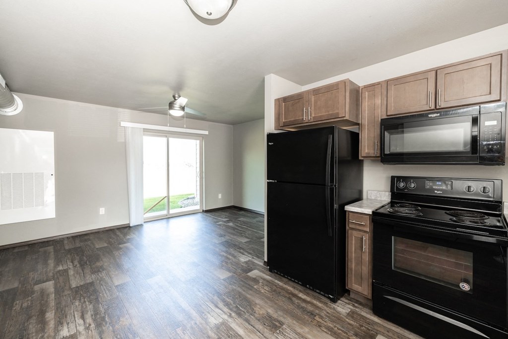an empty kitchen with black appliances and wood flooring