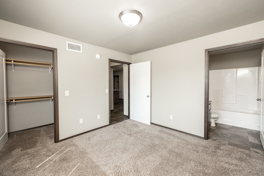 a bedroom with a closet and a bathroom with a mirrored door