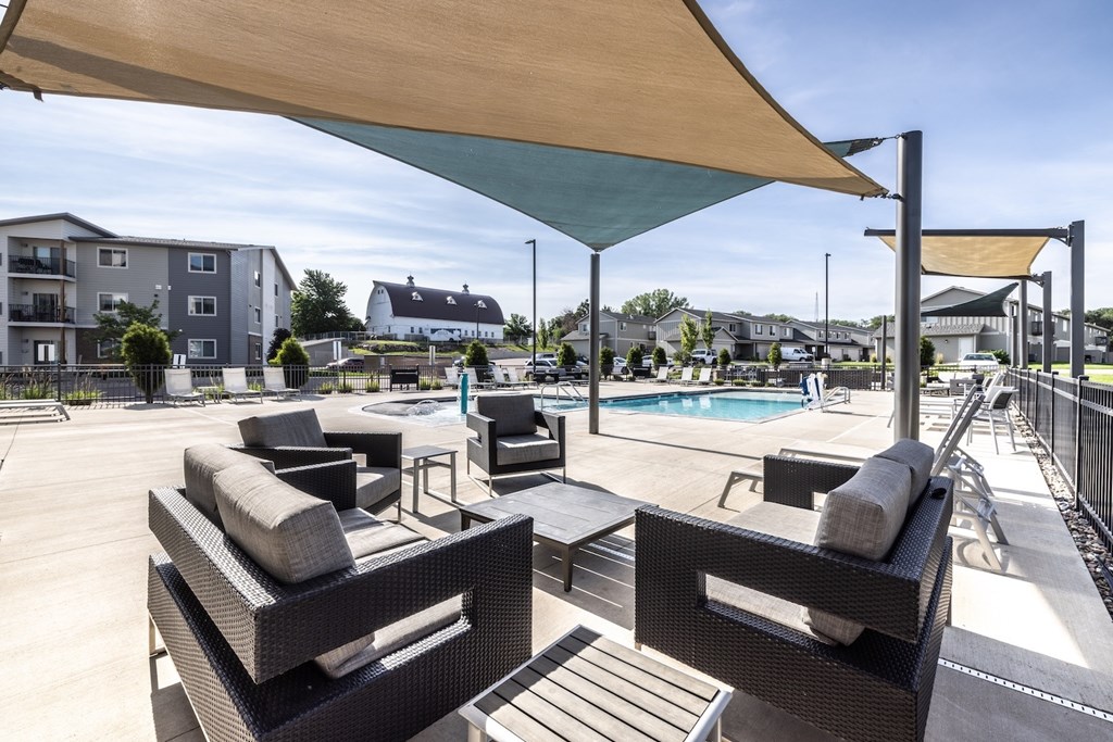 A patio with black wicker furniture and a pool in the background.