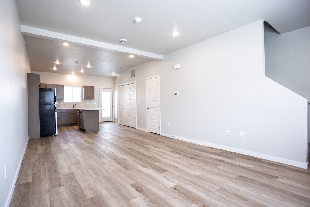 the living room and kitchen of a new home with white walls and wood flooring