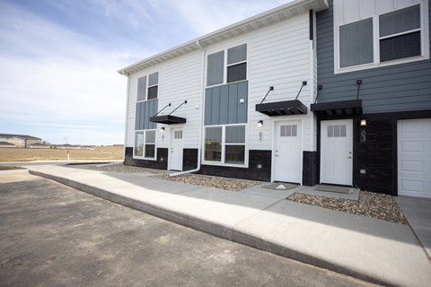 a white and black building with two white doors and a sidewalk