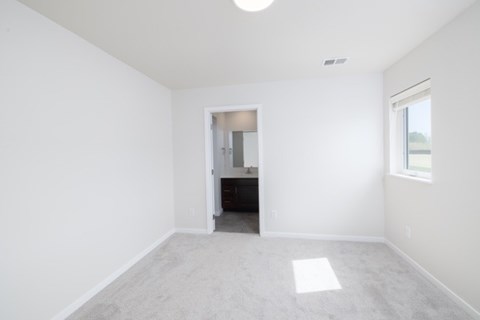 A spacious room with a carpeted floor and a small closet with a door.