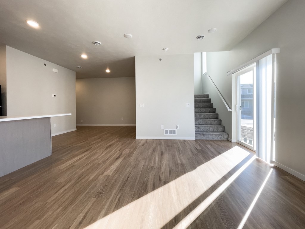 an empty living room with a staircase and a window