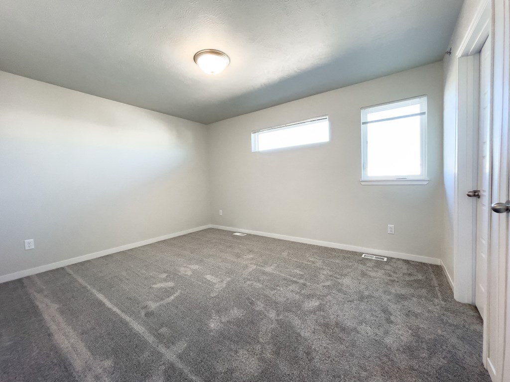 an empty room with carpet and two windows