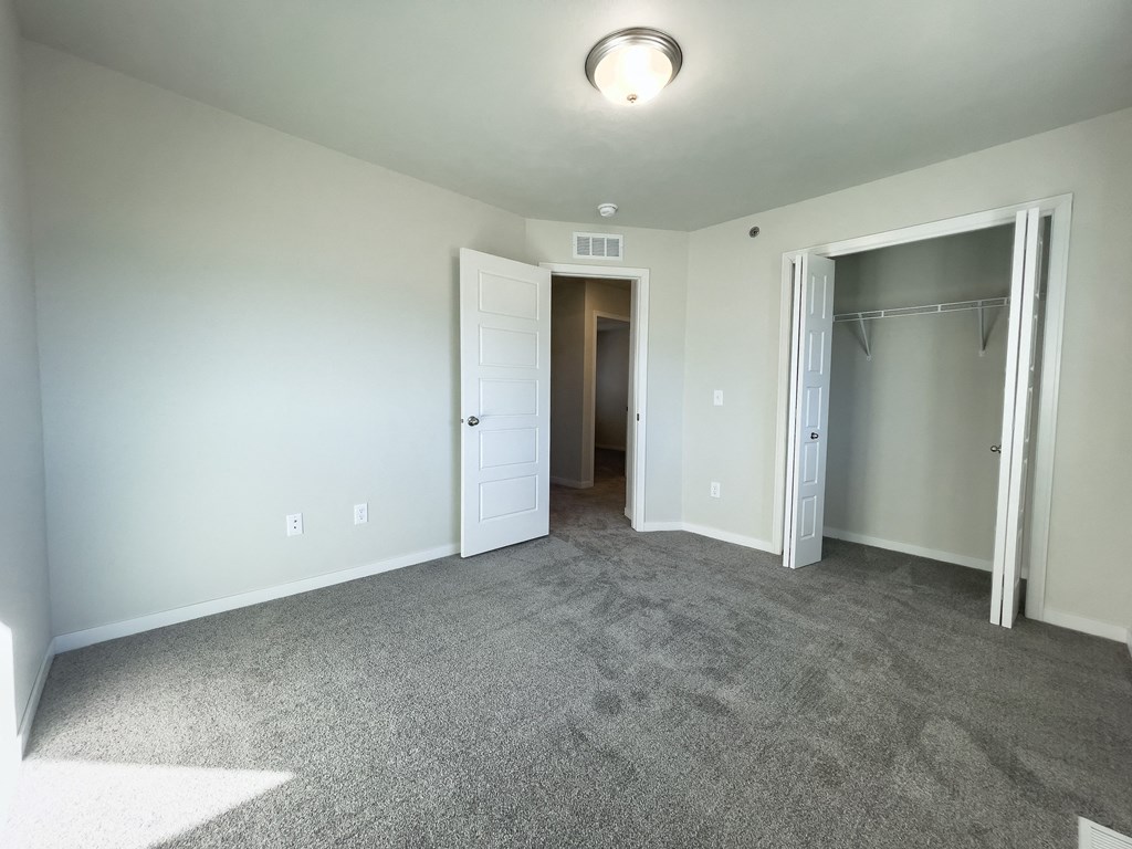 an empty living room with carpet and a door to a closet
