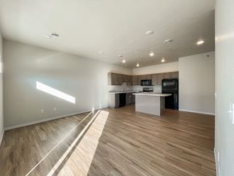 the living room and kitchen of an apartment with wood flooring