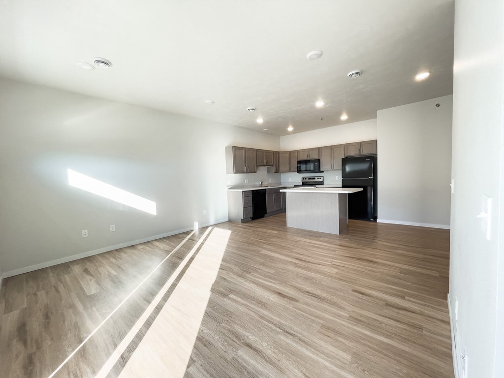 an empty living room and kitchen with wood flooring and