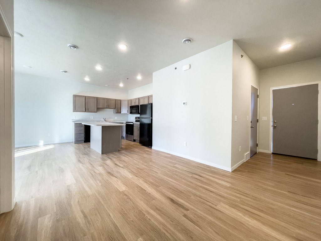 the living room and kitchen of an empty apartment with wood flooring