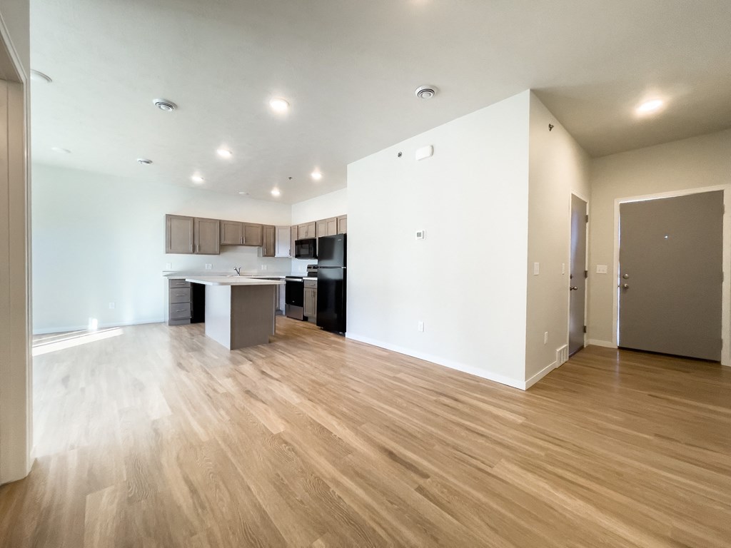 the living room and kitchen of an empty apartment with wood flooring