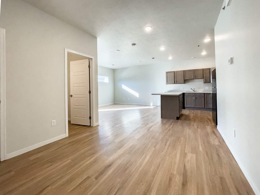 the living room and kitchen of an apartment with wood flooring