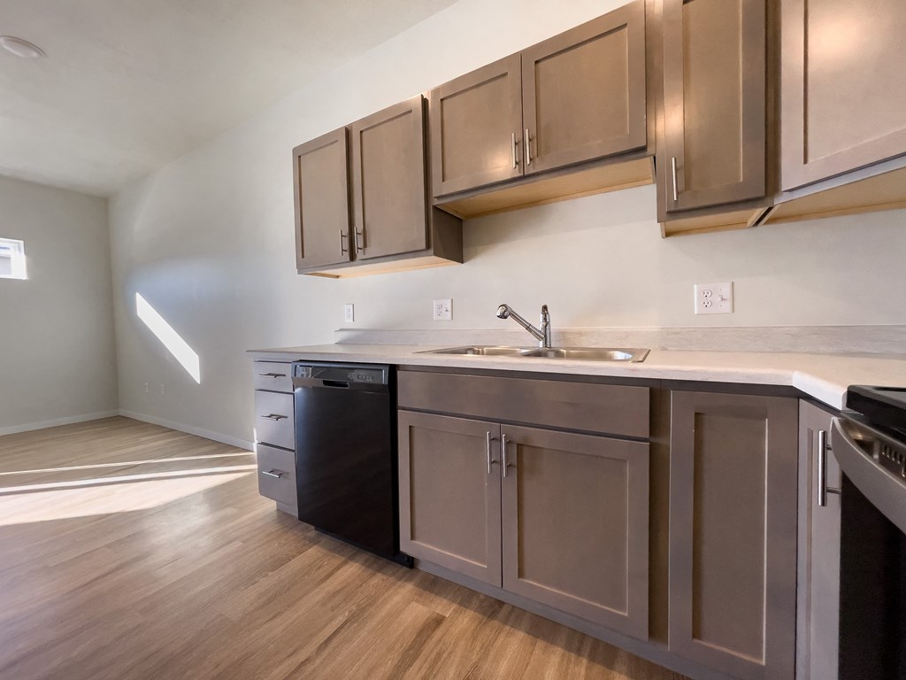 an empty kitchen with stainless steel appliances and wood flooring