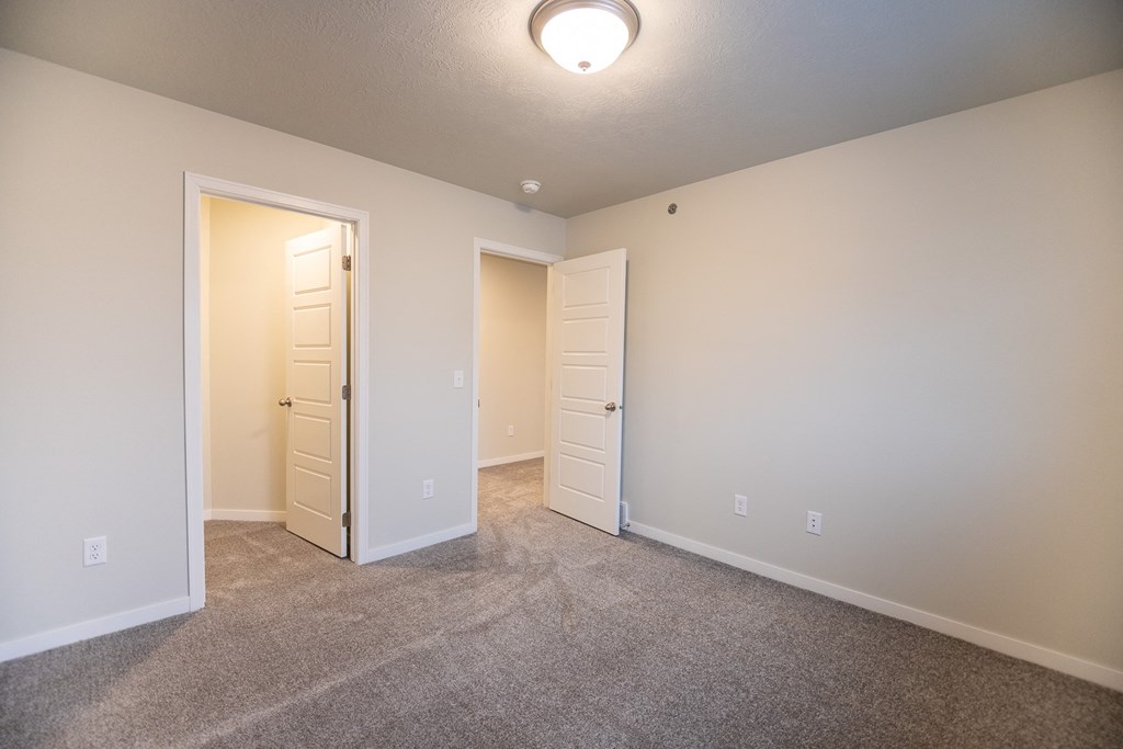 an empty living room with an open door to a bedroom