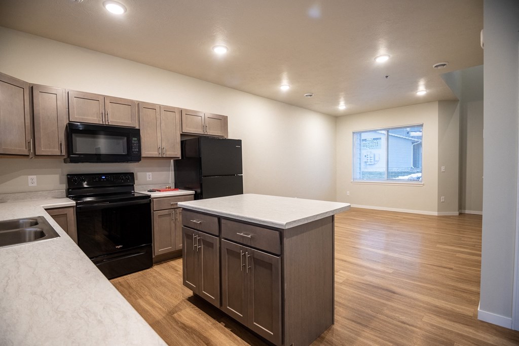an empty kitchen with an island and a black stove and refrigerator