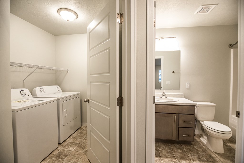 an empty bathroom with a washer and dryer and a toilet