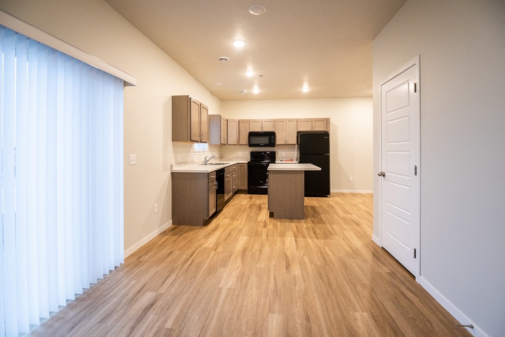 a view of a kitchen and a living room with a wooden floor and a window