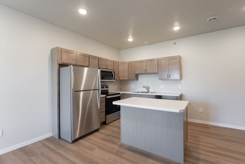 an empty kitchen with stainless steel appliances and a white counter top