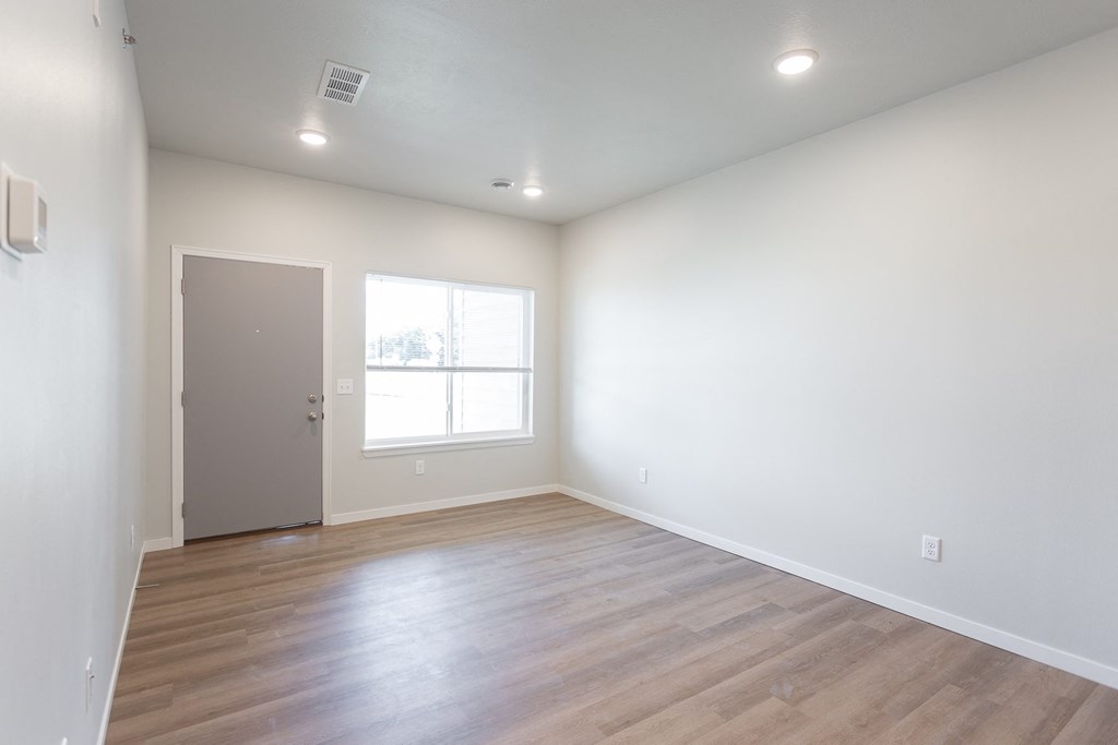 an empty living room with white walls and wood floors