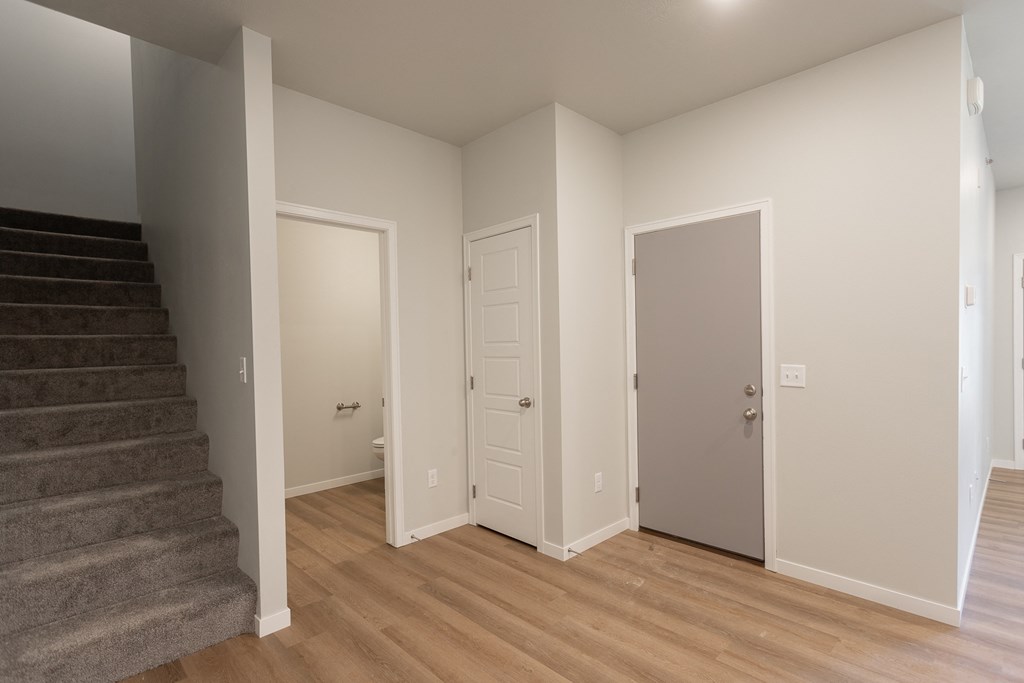 an empty living room with stairs and a door to a bedroom