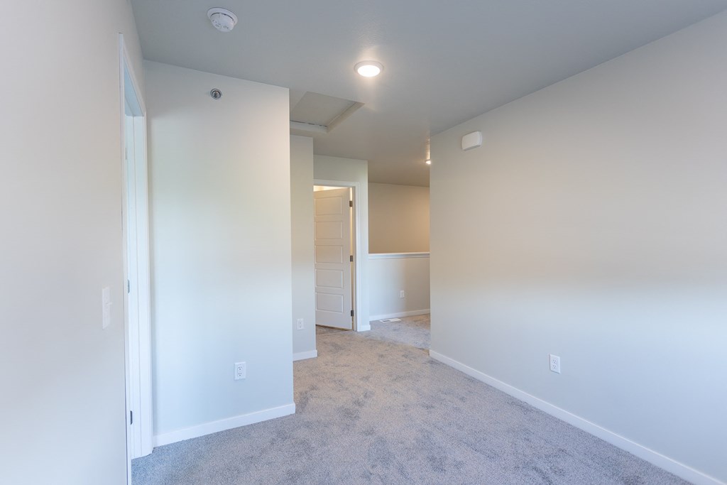 an empty living room and hallway with white walls and carpet