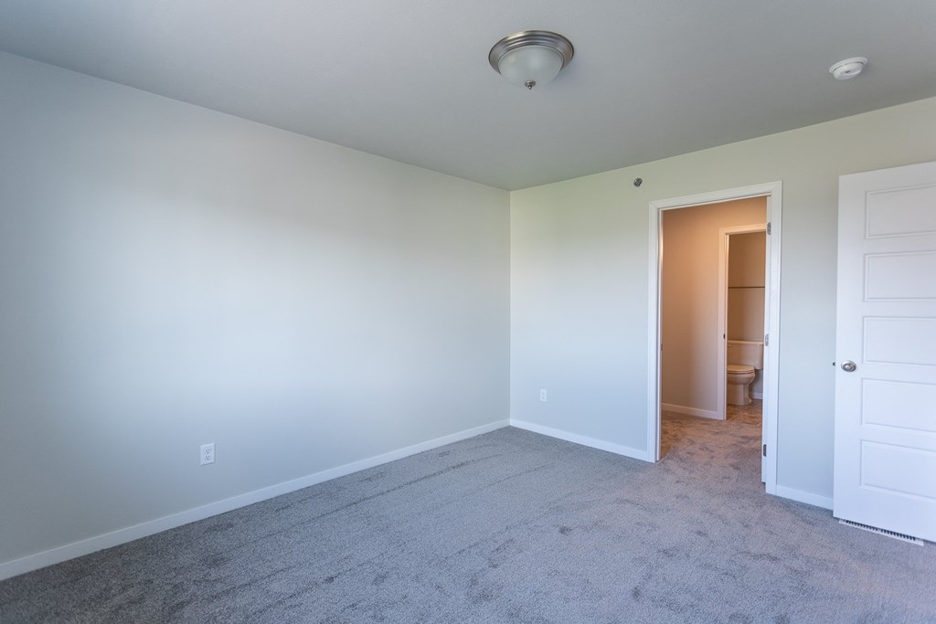 an empty room with white walls and a door to a bathroom