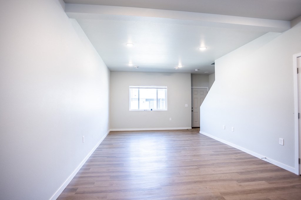 an empty living room with white walls and wood floors