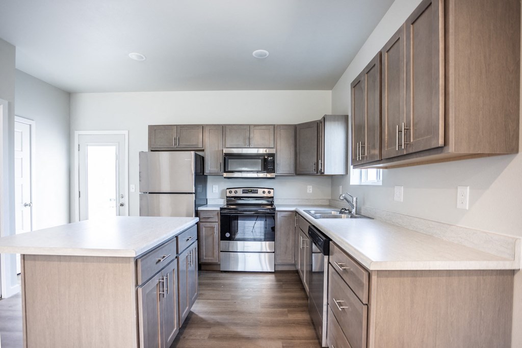 an empty kitchen with wooden cabinets and stainless steel appliances