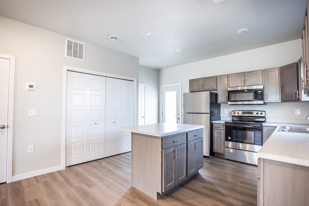 a large kitchen with stainless steel appliances and wooden floors